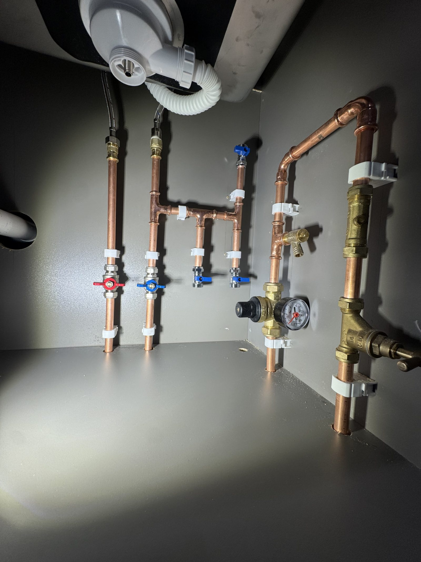 Tidy copper pipework with isolation valves inside a cabinet in a Currie home